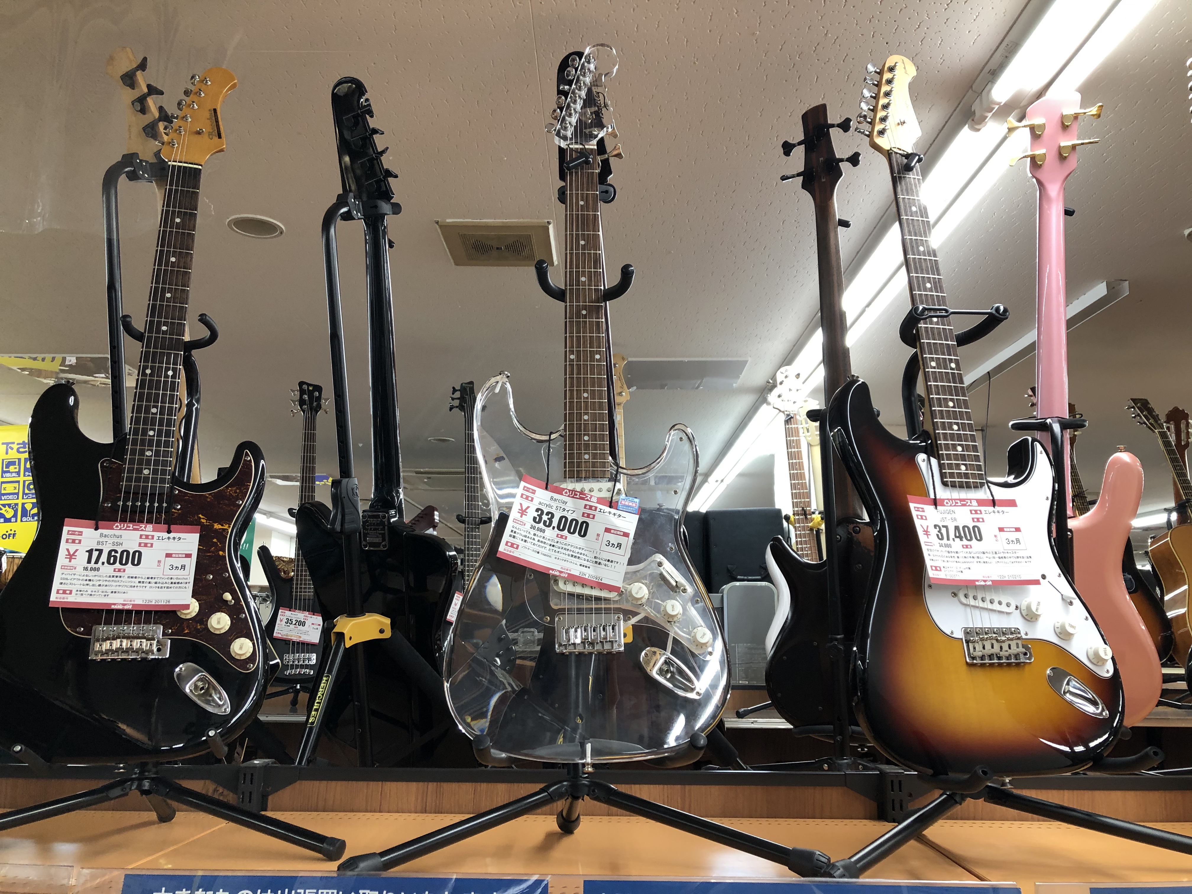 Three guitars in a second-hand store. One is clear acrylic. Photo by Denisse Rauda.
